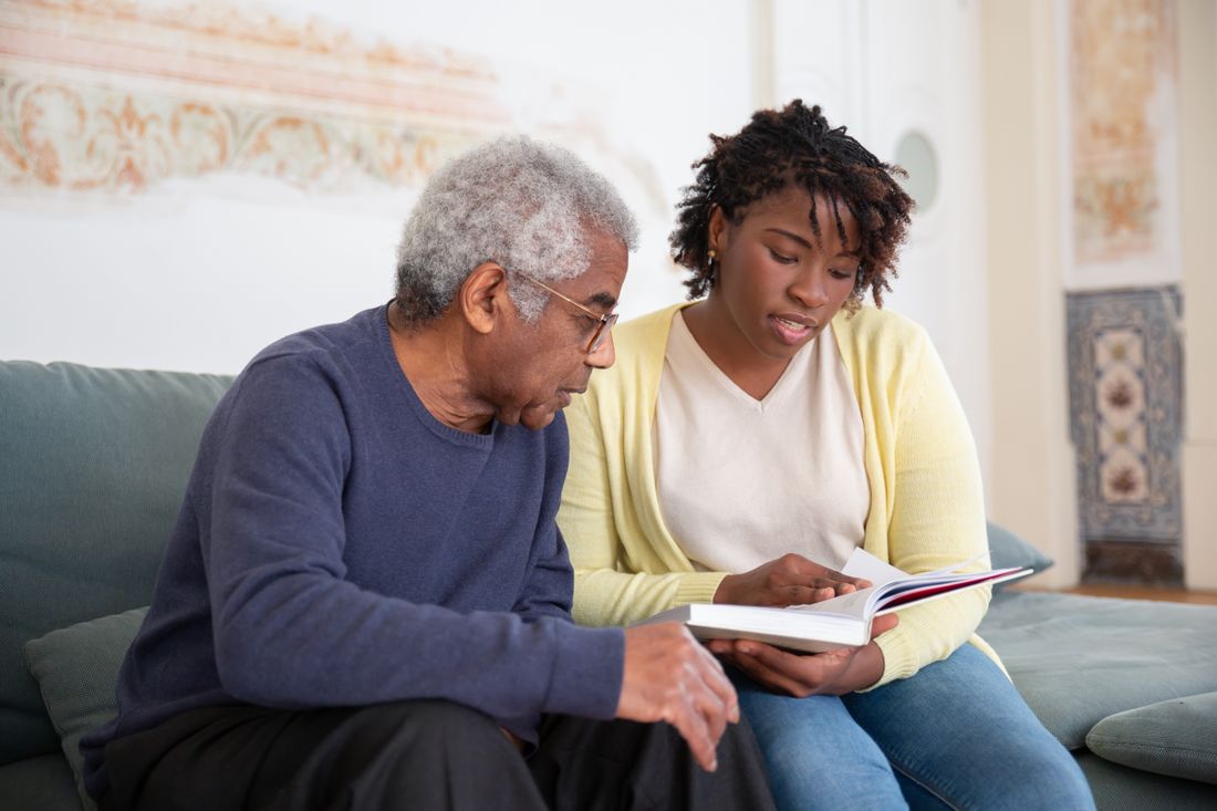 A caregiver and client reading together at home