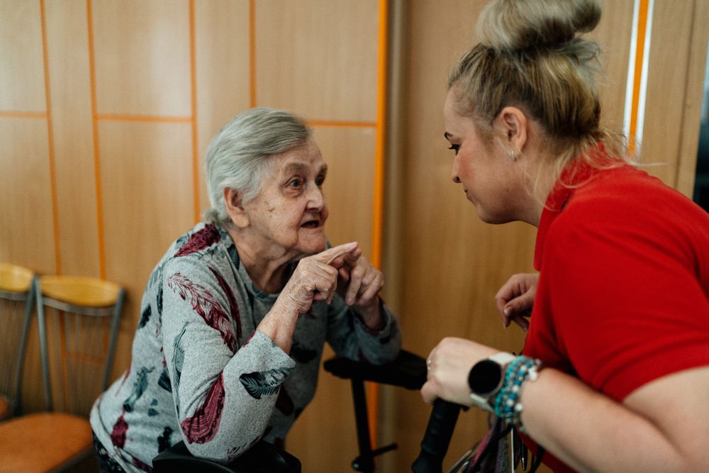A caregiver and senior sharing a warm conversation at home